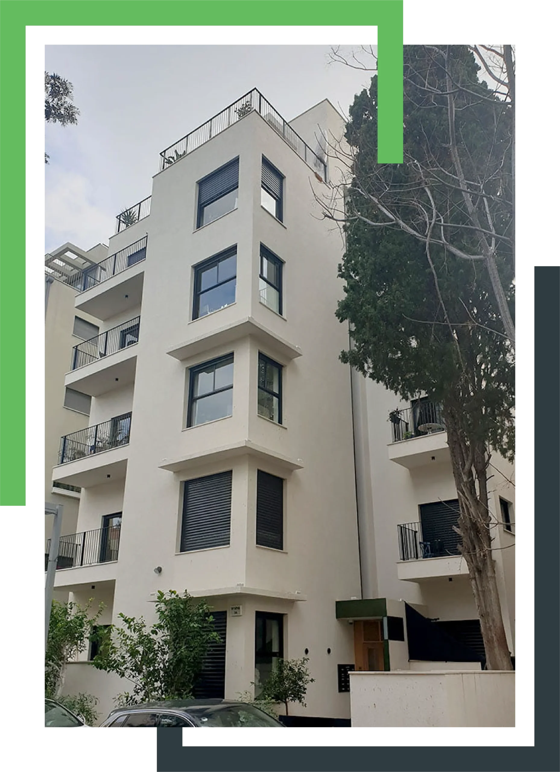 בניין מגורים בעל עיצוב מודרני עם חלונות גדולים ומרפסות עם מעקות ברזל, מוקף בצמחייה ועצים.